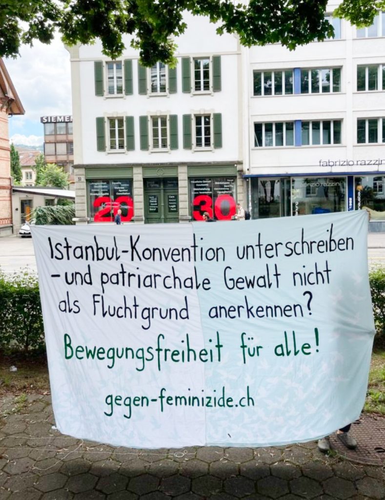 Ein Banner im öffentlichen Raum mit der Aufschrift «Istanbul-Konvention unterschreiben – und patriarchale Gewalt nicht als Fluchtgrund anerkennen? Bewegungsfreiheit für alle! gegen-feminizide.ch»