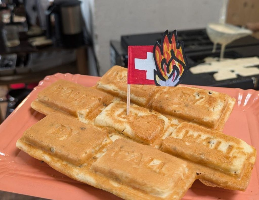 Crêpe in der Form einzelner Mauerblöcke mit den Worten «Brick by Brick by Brick» eingraviert und einem gebastelten brennenden Schweizerfähnchen.