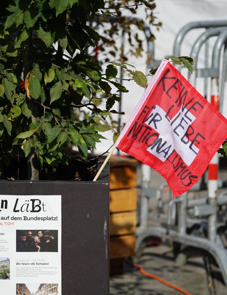 Modifiziertes Schweizerfähnchen steckt in einem Pflanzentopf. Auf dem Fähnchen steht jetzt «Keine Liebe für Nationalismus»