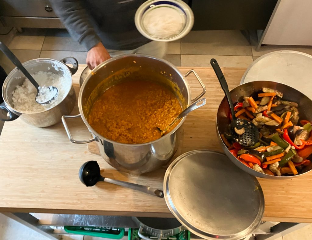 Grosse Töpfe voller Essen: Reis, Daal und Gemüse. eine Person ist gerade dabei, sich den Teller zu füllen